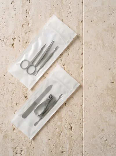 Instrumentos de manicure em embalagem de esterilização selada, sobre bancada de pedra